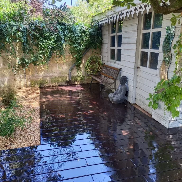 Cour pavée ombragée avec banc et bassin, sol sombre après la pluie