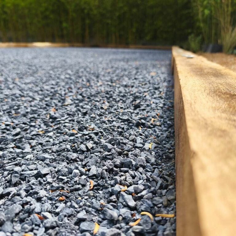 Gravillon concassé gris et bordure en chêne d'un terrain de pétanque